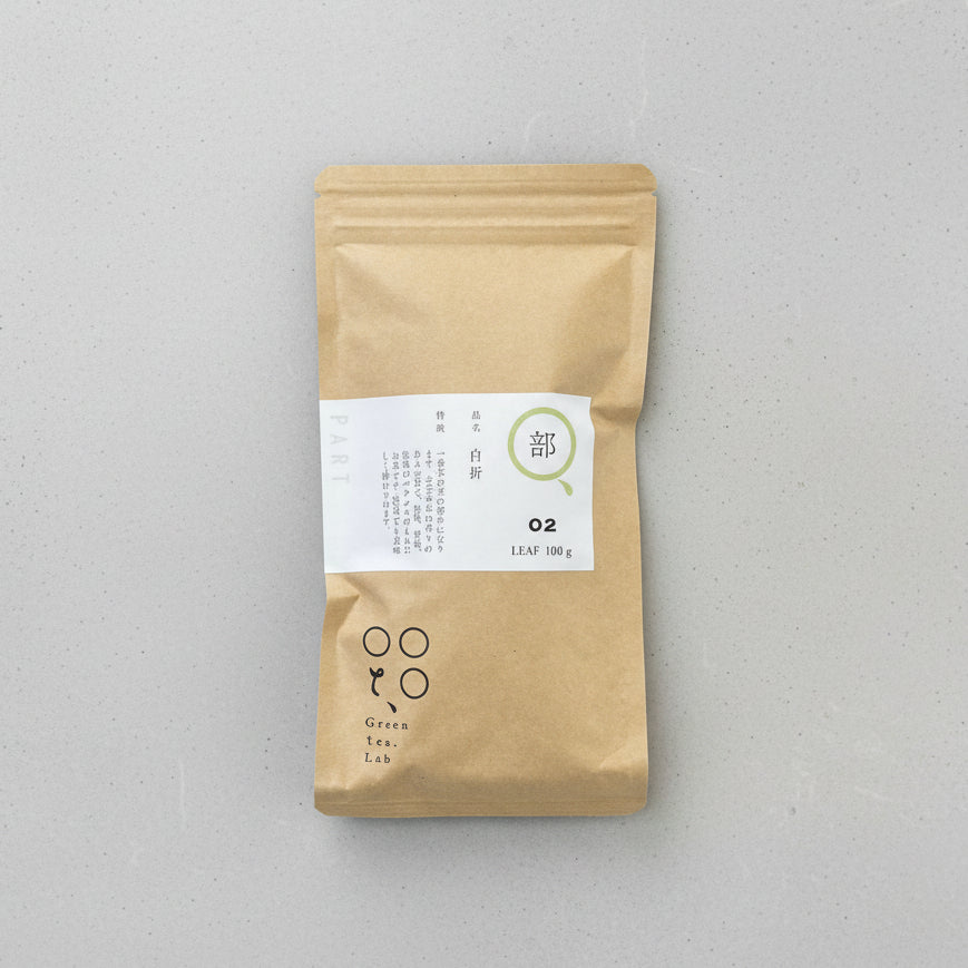 A packaged bag of Tomizawa Tea Garden's Kumamoto Shira-ore Leaf Stem Tea with a label indicating it's a naturally grown green tea product.